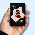 Hand holding a card with an enamel pin badge featuring a red asthma inhaler design with the text 'it ain't easy being wheezy'.