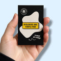 Enamel pin badge packaging with a humorous message saying 'dyslexics are teople poo' held in a hand against a light blue background.