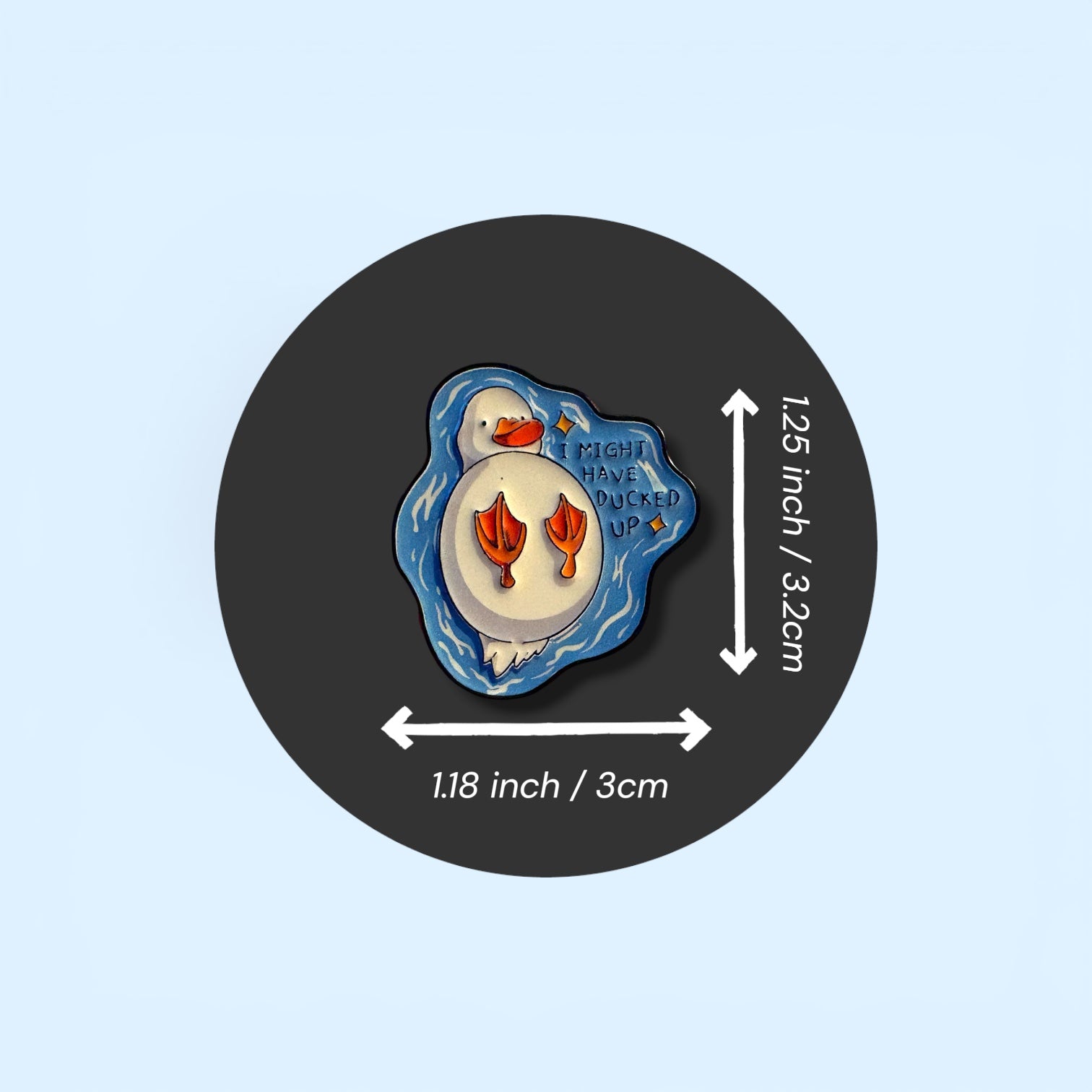 Pin with measurements on a black circle against a light blue background. Enamel pin badge on the black circle of a duck swimming on it's back with the text 'I might have ducked up' 