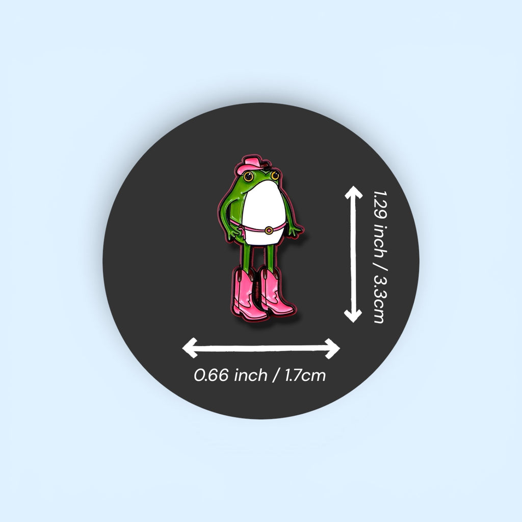 Pin with a frog character wearing pink boots and a hat, shown with measurements on a dark background.